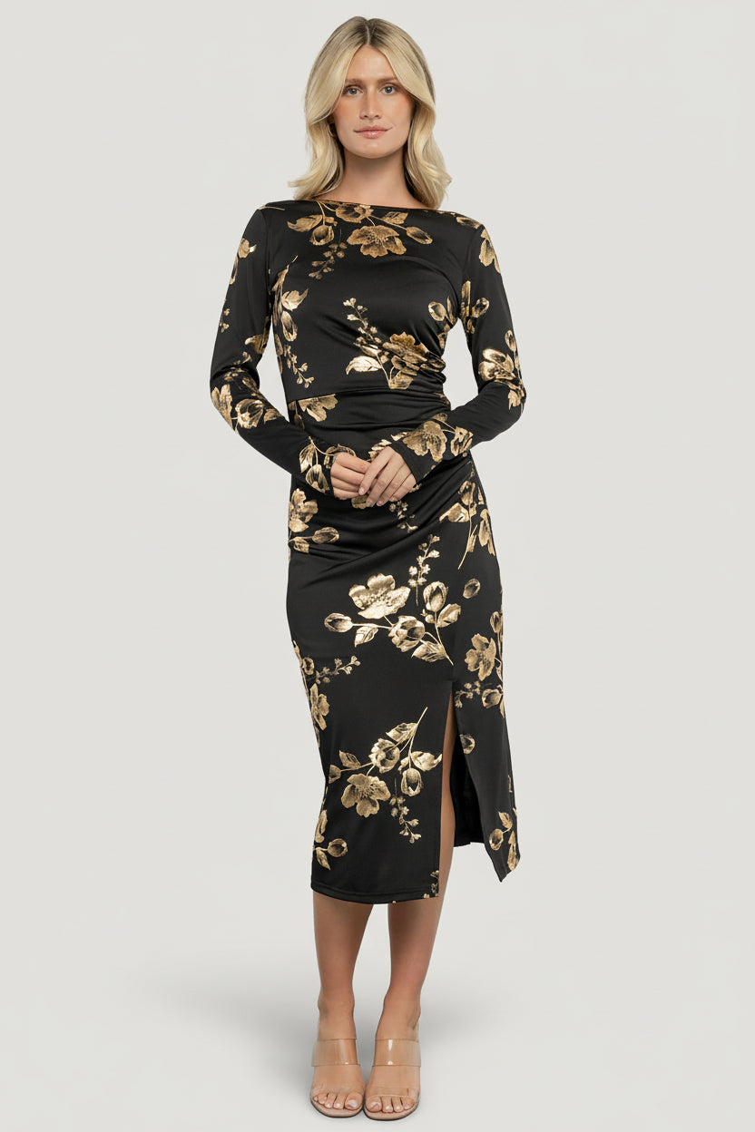 Model front view wearing Valeria Midi Dress in black with gold metallic floral pattern, boat neckline and fitted bodice.