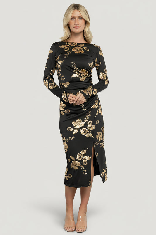 Model front view wearing Valeria Midi Dress in black with gold metallic floral pattern, boat neckline and fitted bodice.