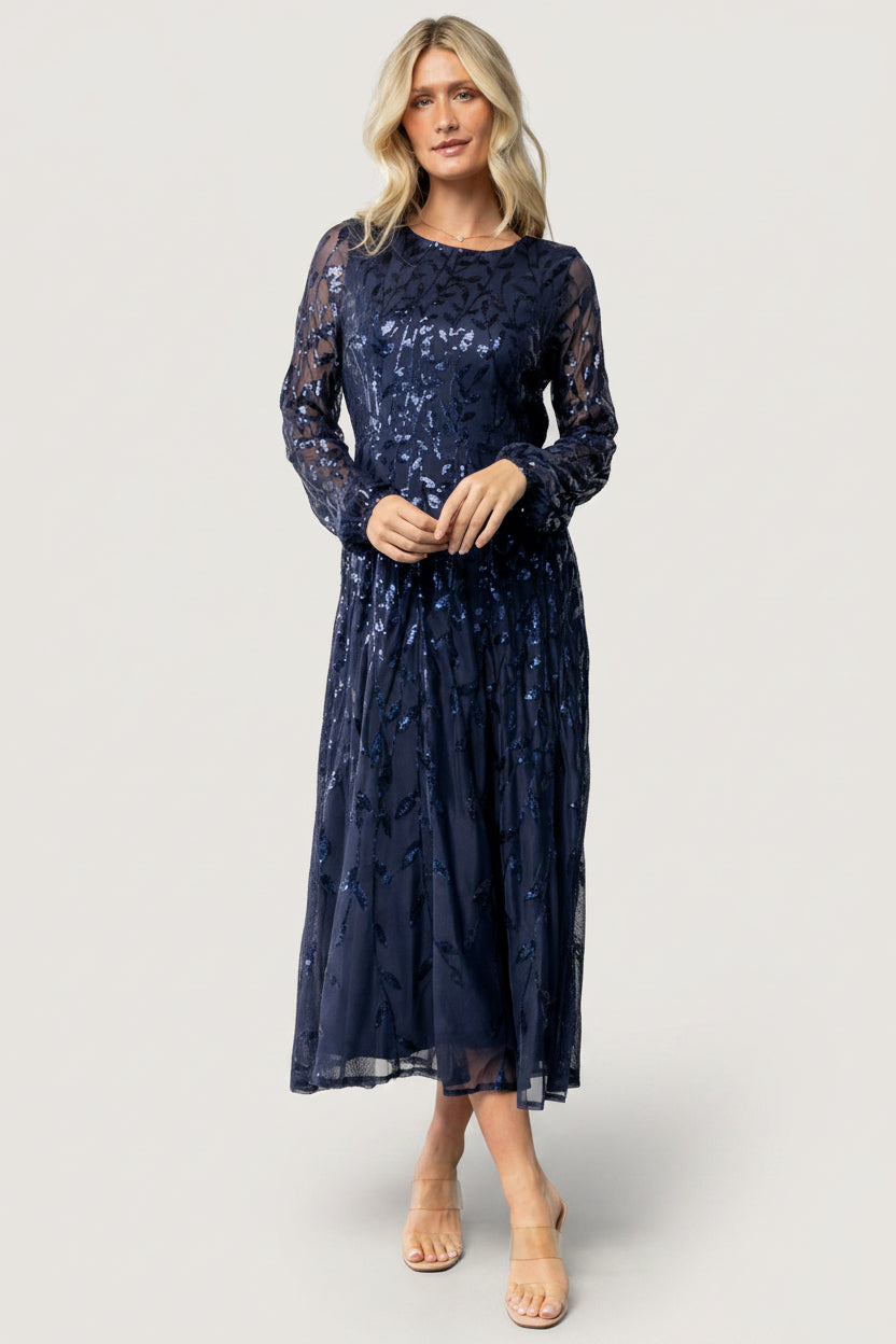 Front view of navy Kalla sequin mesh midi dress on model, A-line silhouette, long sheer sequin-embellished sleeves and round neckline.