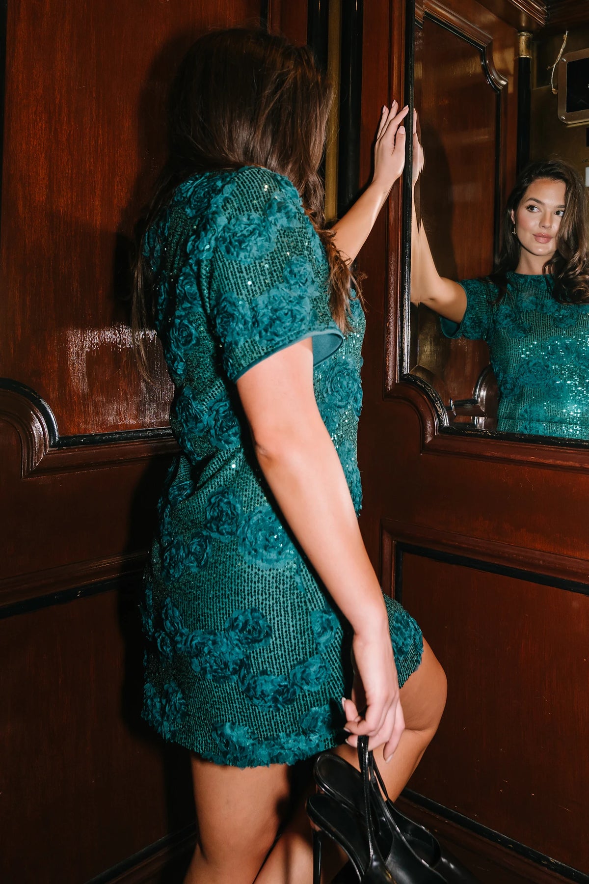 Model wearing a green short shift dress embellished with green sequins and floral appliqué detailing.