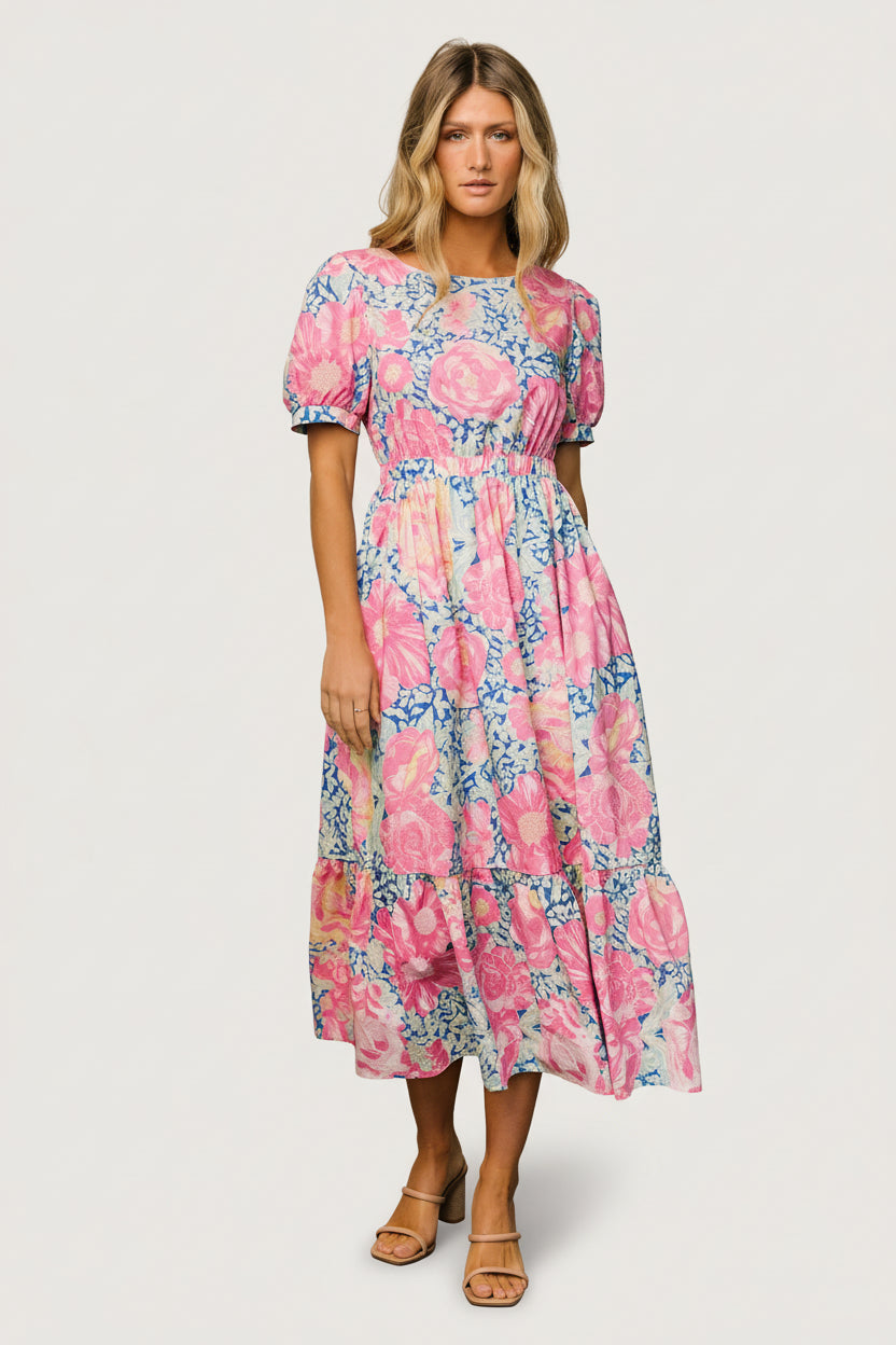 Model front view wearing blue and pink floral midi dress, round neckline, short sleeves, elastic waist, and side pockets.