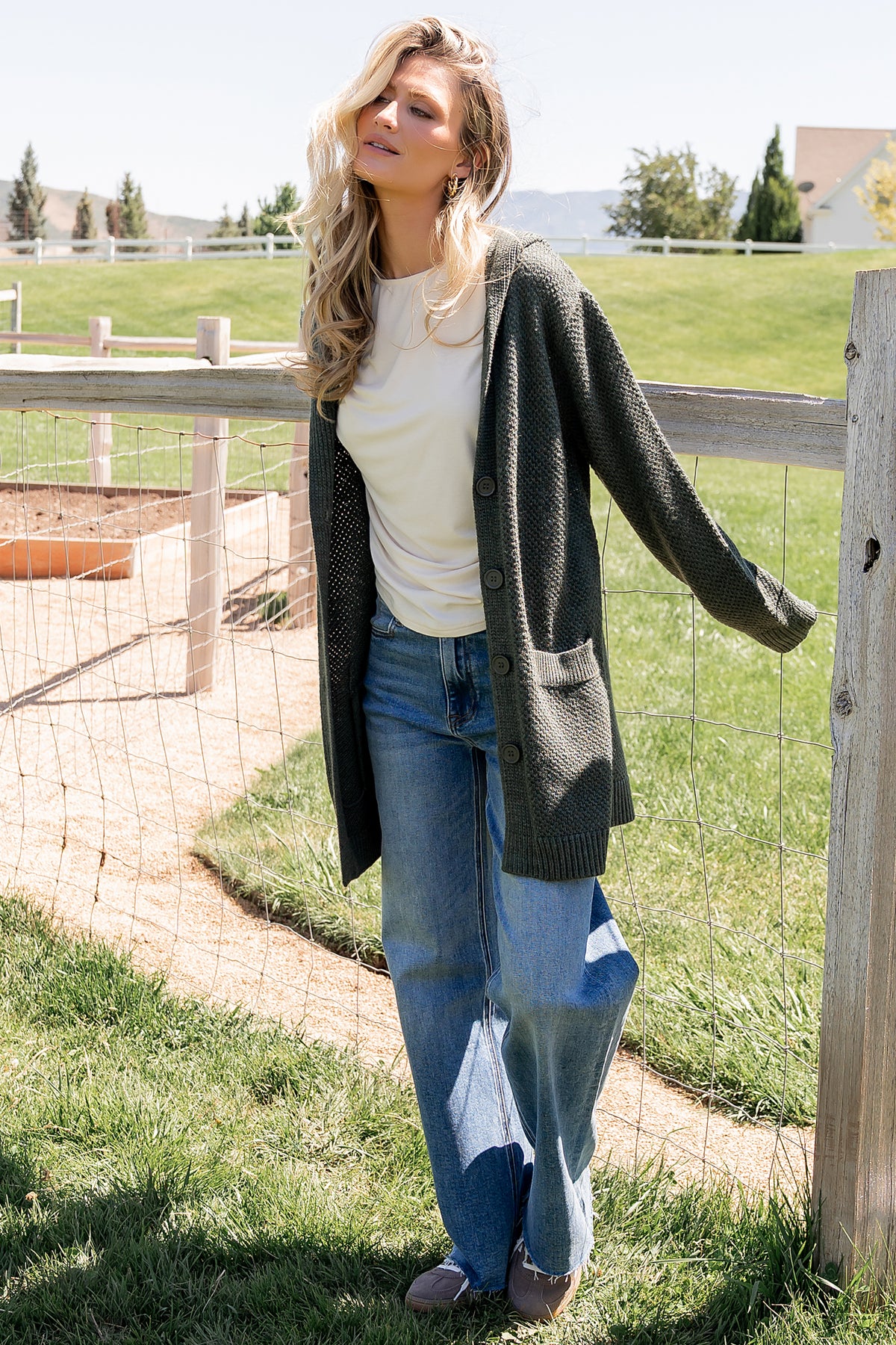 Back view of the Katrine hooded cardigan in deep green showing relaxed silhouette, hood shape, and hemline length over casual outfit.