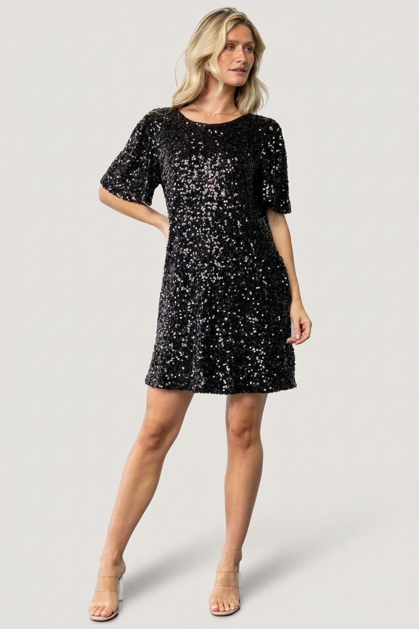 Front view of a black short sequin shift dress with round neckline, short sleeves, and subtle shimmer across the fabric, shown on a model.