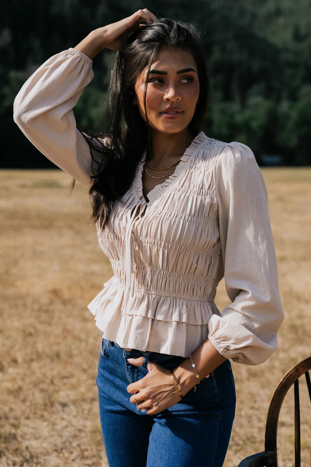 Marnie Smocked Top in Natural with smocked bodice, front bow ties, long sleeves, elastic cuffs, and peplum hem.
