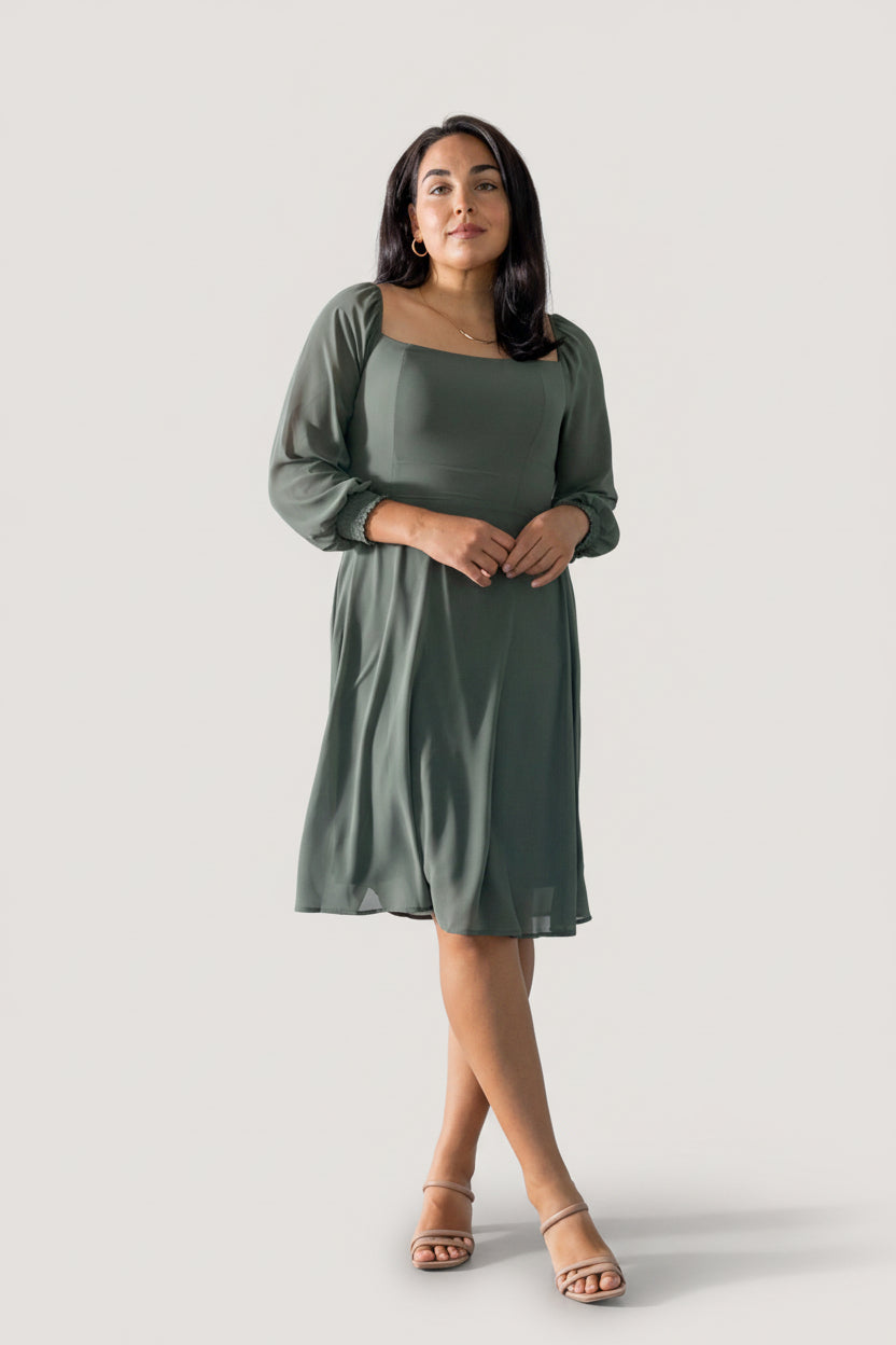 Side view of short chiffon dress in dark sage highlighting lined skirt and airy sleeves with smocked cuffs