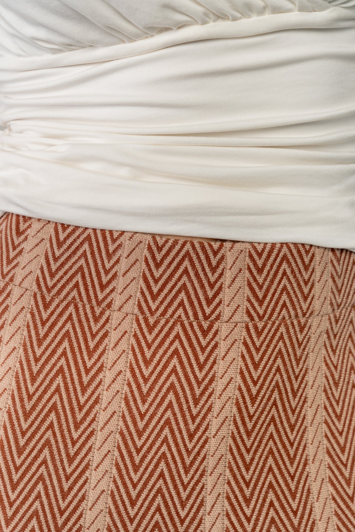 Side view of Astrid Midi Skirt highlighting A-line shape and mid-calf length in rust chevron knit fabric on model.