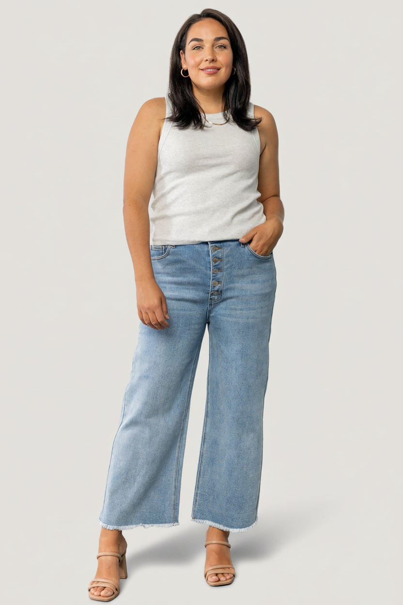 Close-up of Brody jeans fabric and raw hem, displaying light-wash denim texture, subtle whiskering, and stitched button-front detail.