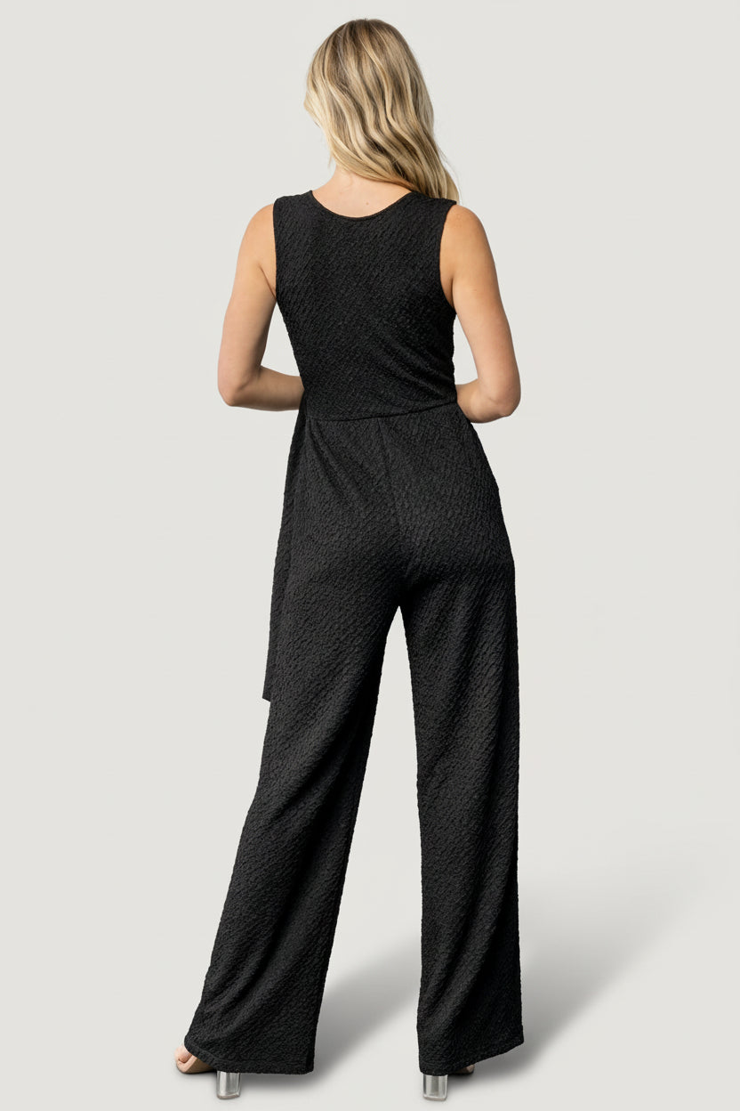 Side view of jumpsuit showing faux-wrap adjustable side tie, elasticized waist, and discreet side pocket placement.