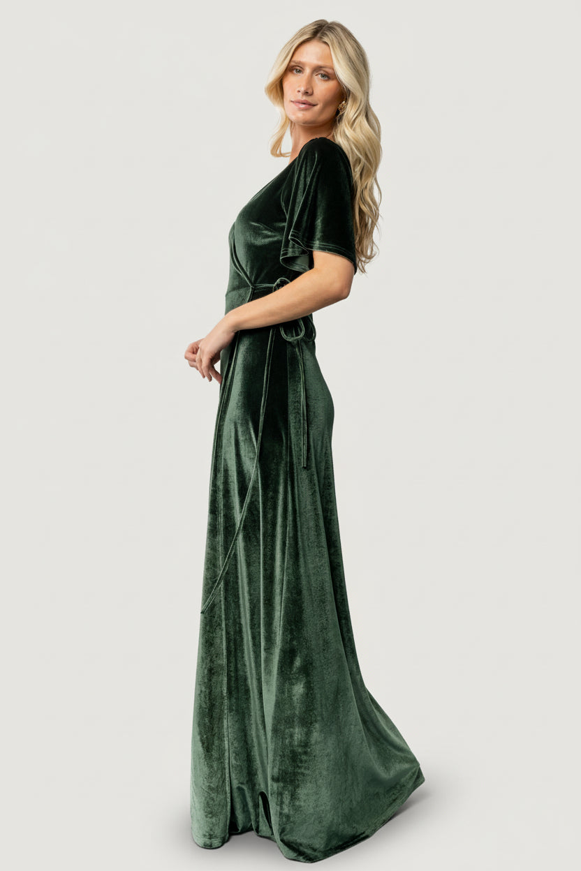 Studio image of the Meghan Velvet Wrap Maxi Dress in deep green, styled for occasion wear with elegant drape and a flattering V-neckline.