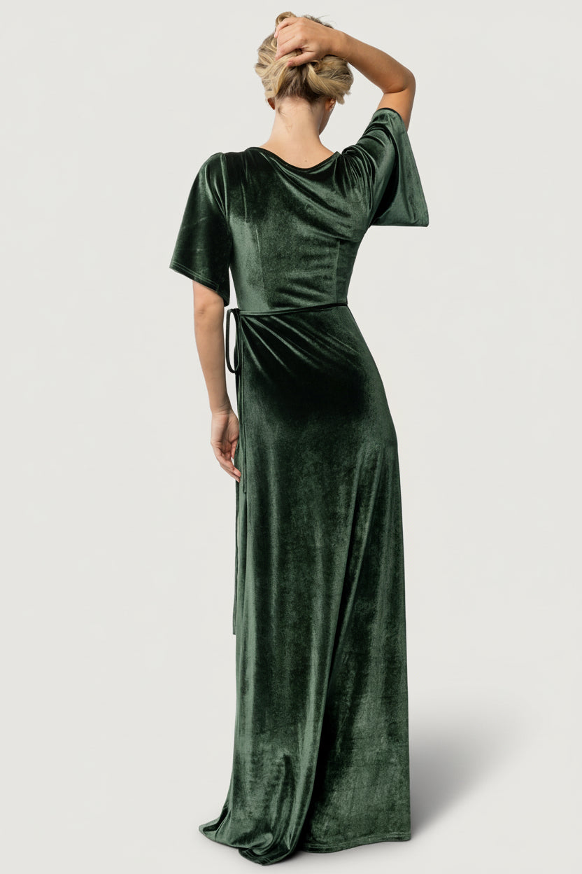 Back view of model in the deep-green Meghan wrap maxi dress, showing full-length skirt, gentle drape, and waist tie detail.