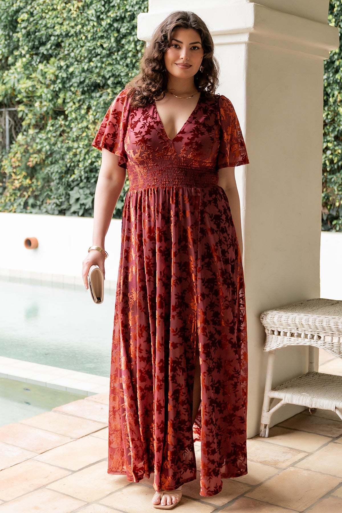 Back and sleeve detail of Veronica velvet maxi dress in rust, showing unlined flowy sleeves and skirt movement.