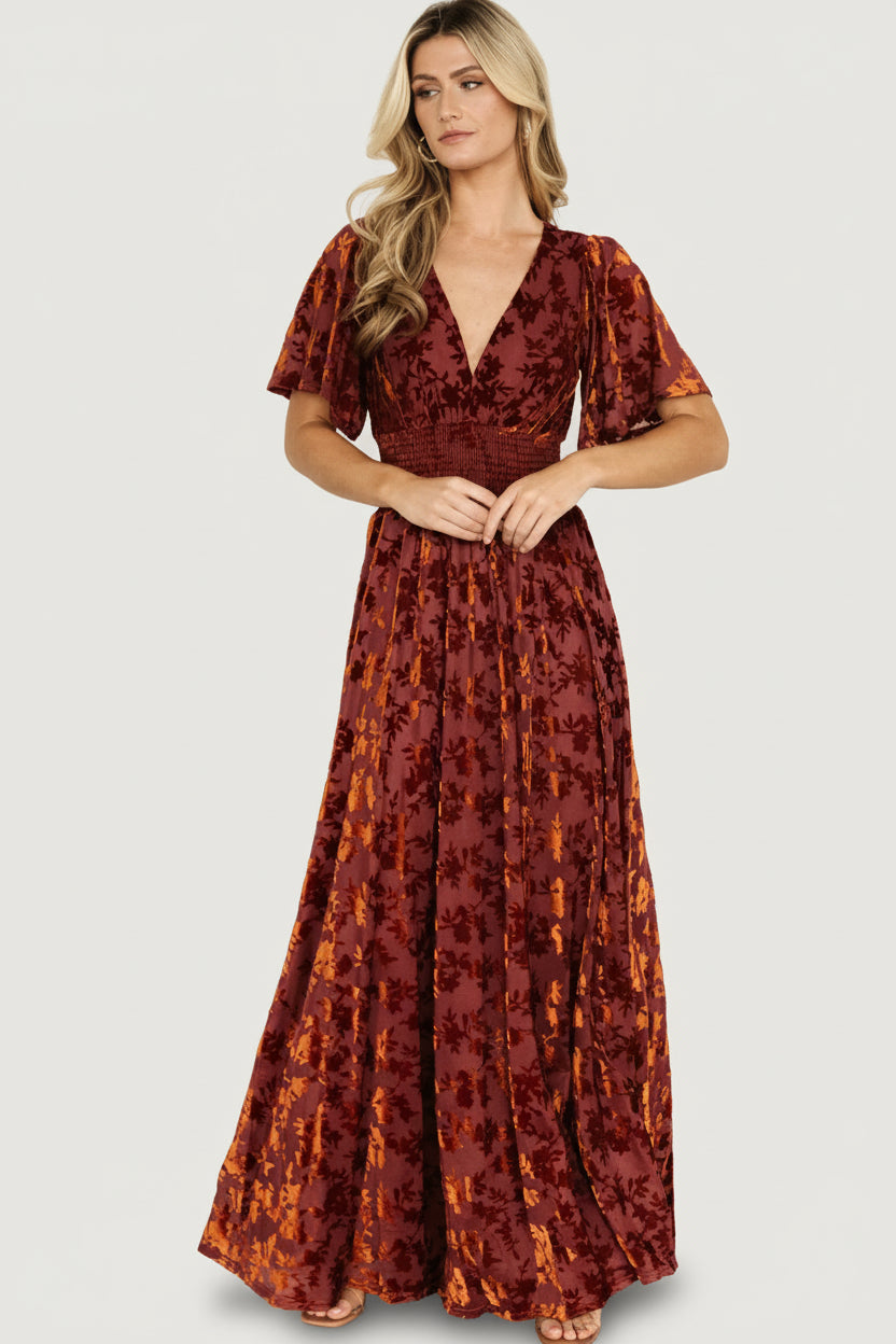 Front model wearing Veronica embossed velvet maxi dress in rust, showing deep V-neck, smocked waist, and left leg slit.