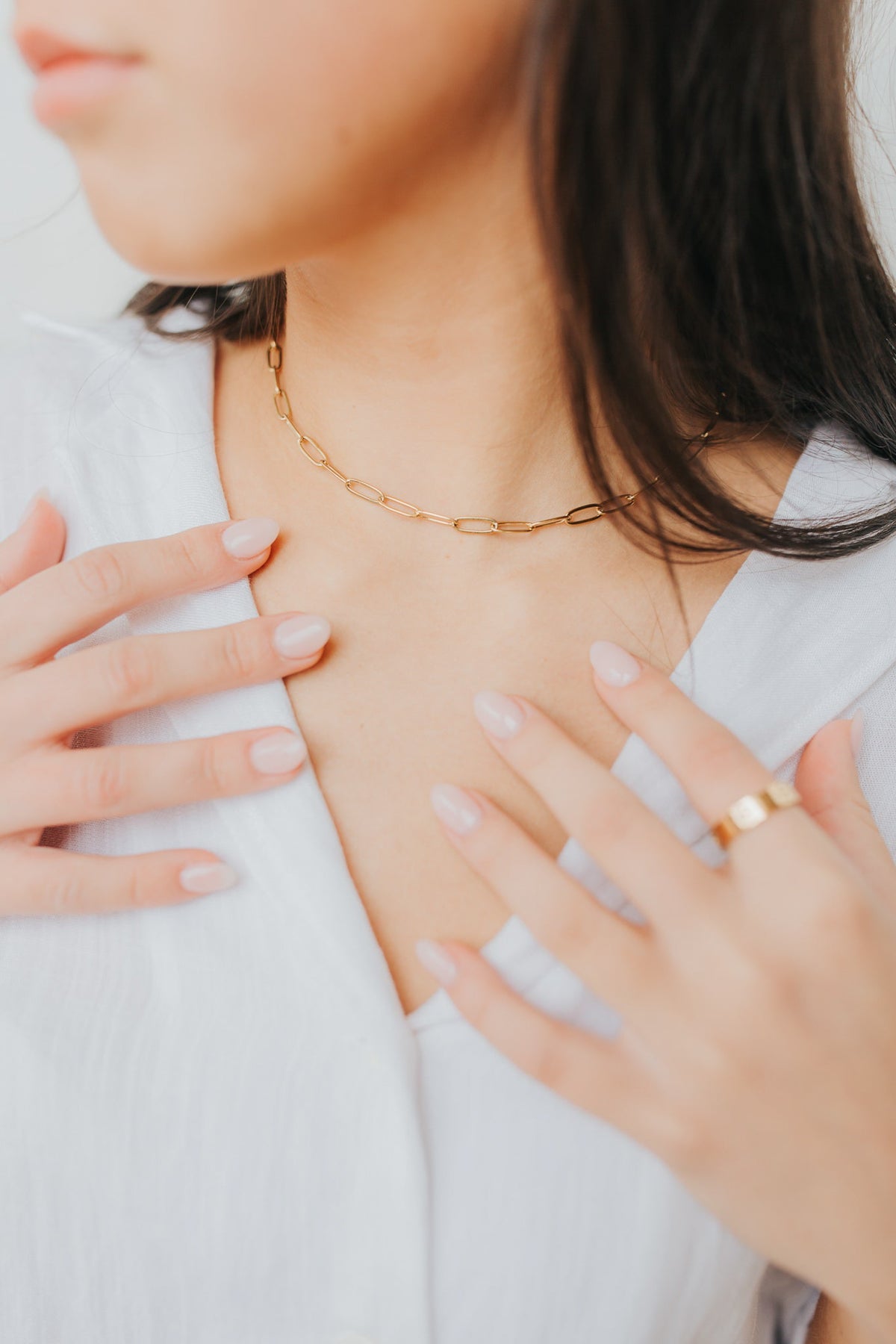 Front-facing image of The Eloise Necklace resting on a simple display, highlighting the elongated chain links and smooth gold-plated surface.