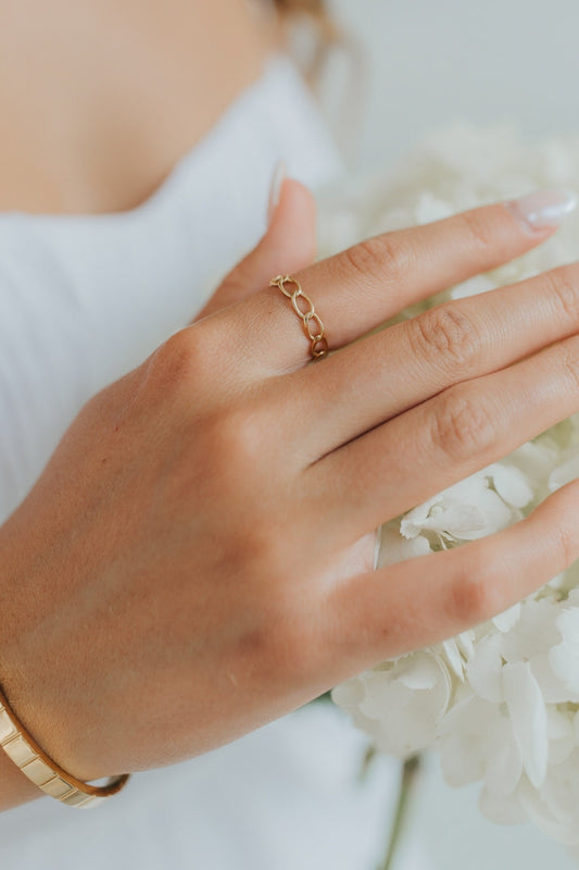 Close-up of The Emma Ring showing polished 18K gold-plated chain-link band on a neutral background, highlighting link detail and finish.