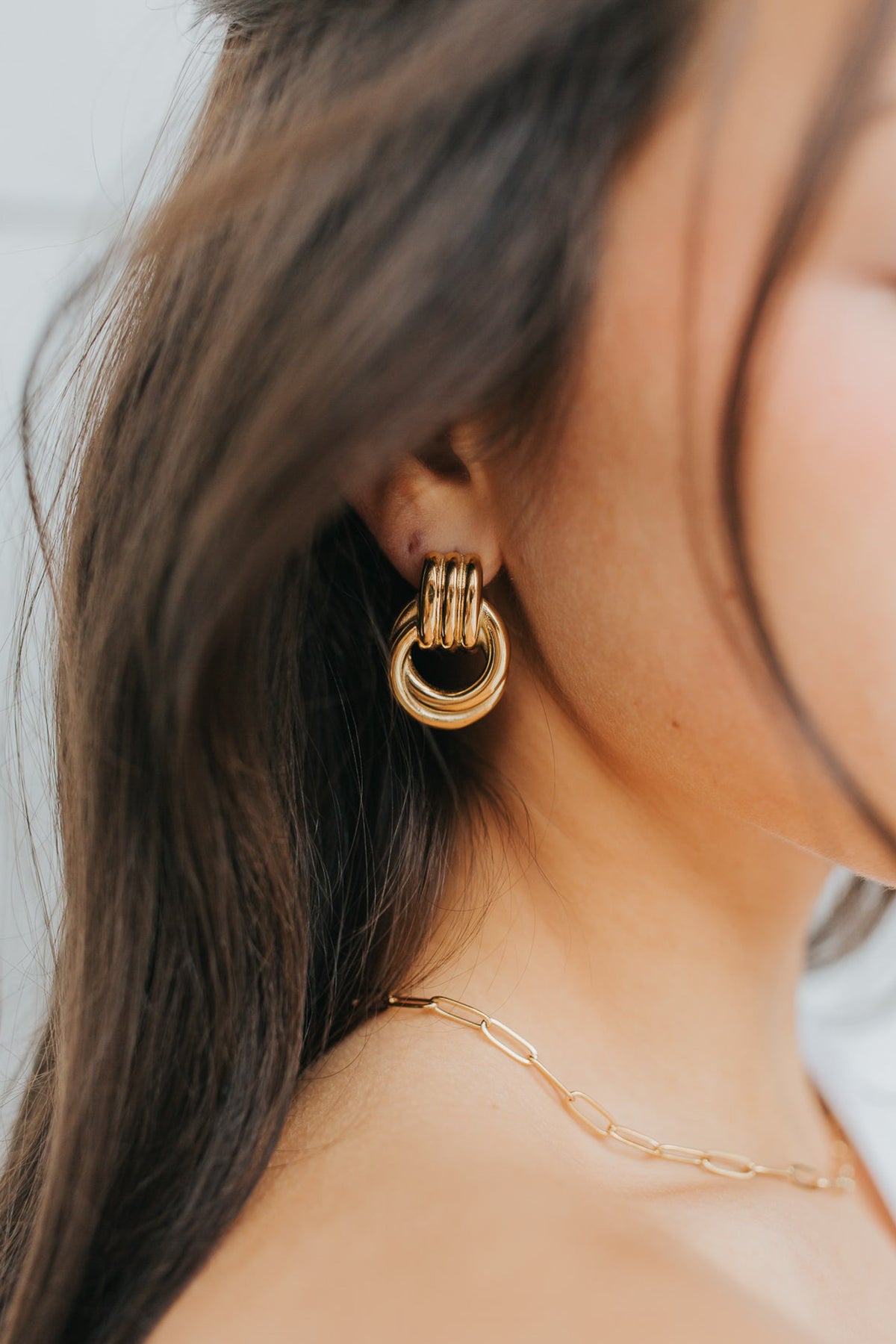 Model wearing gold Hailey Earrings with Eloise necklace; close-up shows interlocking hoop silhouette, polished finish, and secure post-back closure.