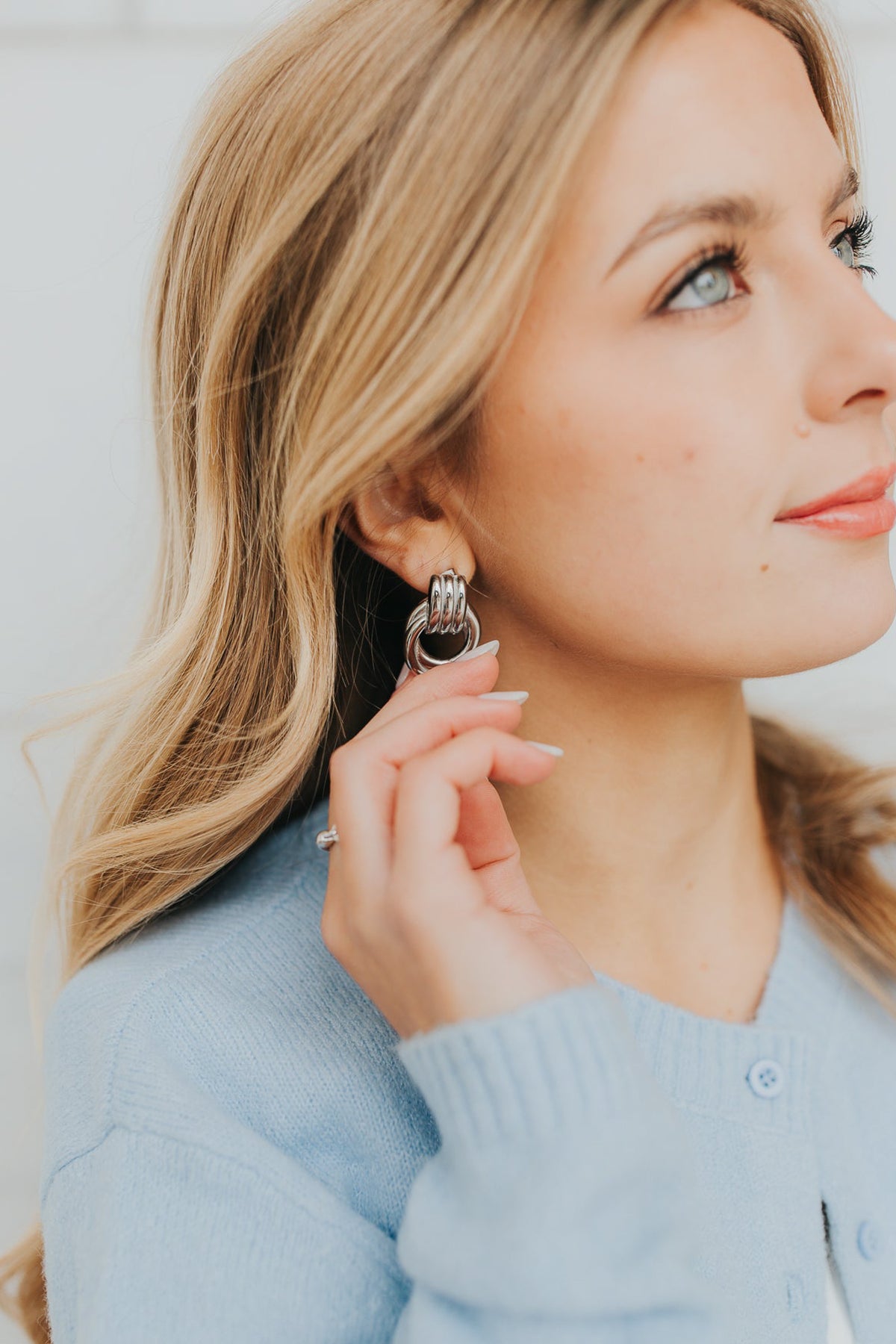 Model close-up wearing silver Hailey Earrings with minimal makeup; emphasis on interlocking hoops, polished shine, and everyday elegance.