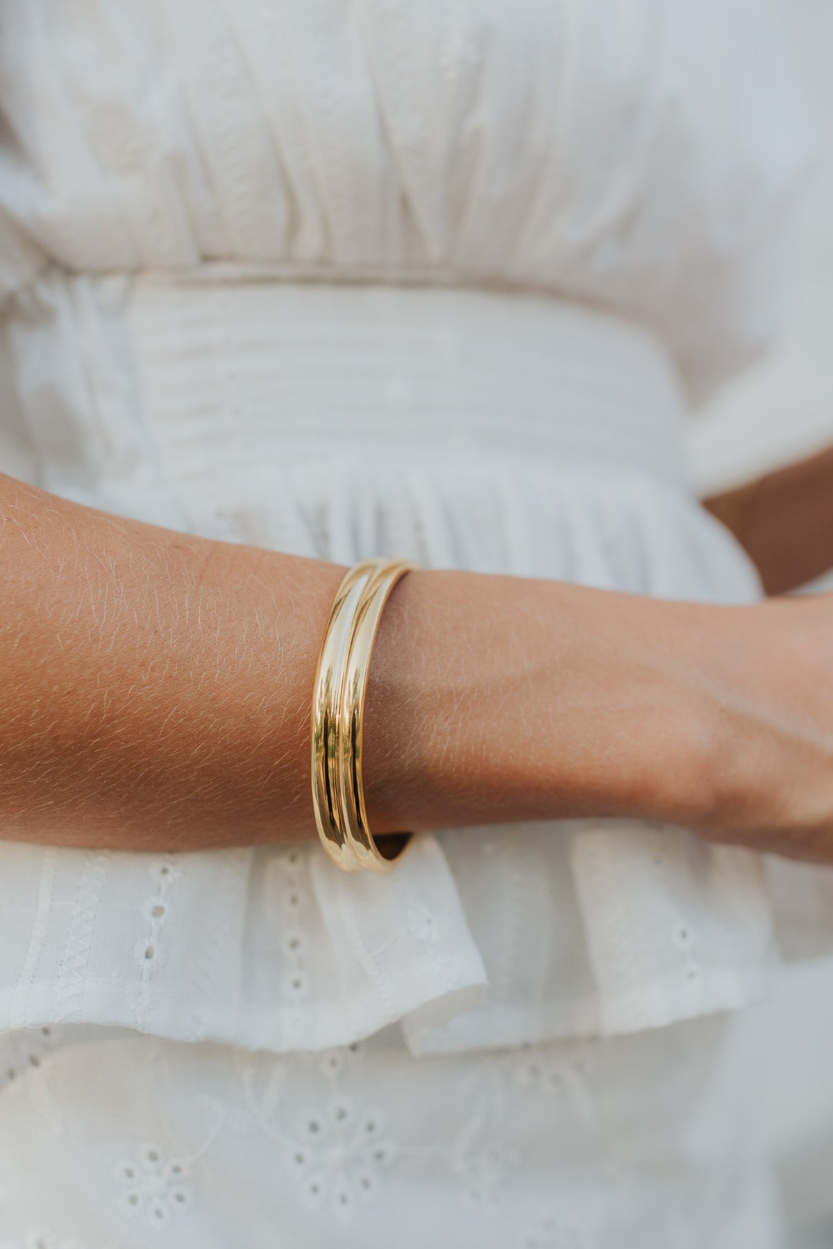 High-polish 18K gold open cuff bracelet at three-quarter angle highlighting dual-bar detail and smooth interior curve for comfort.