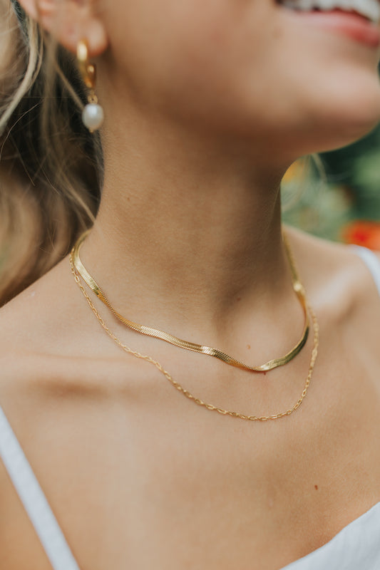 Close-up of the Christina layered double-chain necklace in warm gold, showing both fine chains, lobster clasp, and delicate finish on white background.