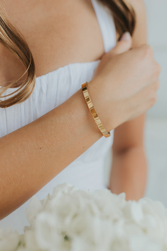 Close-up of the Lily Bracelet in 18K gold-plated finish, showing high-gloss surface and soft beveled edge against a neutral backdrop.