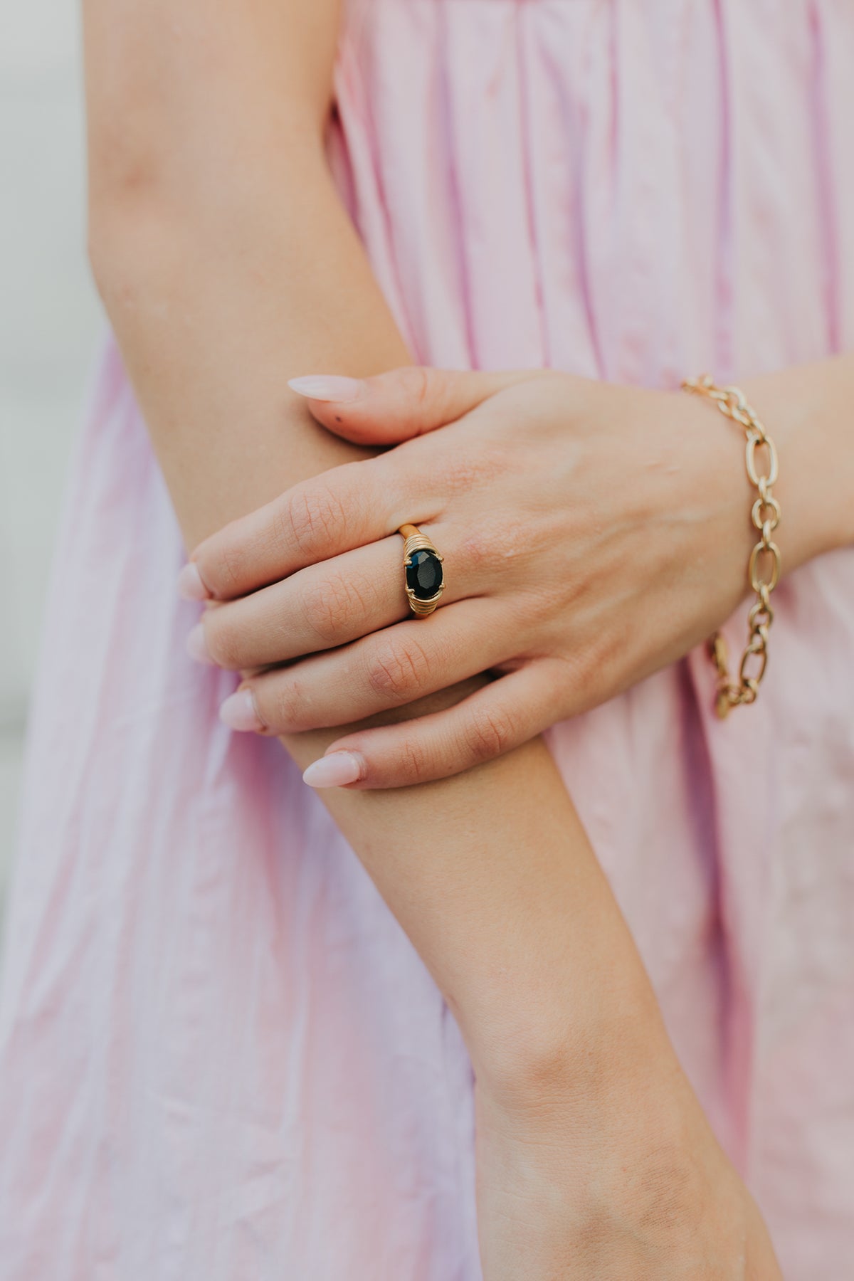 Angled studio shot of Maddie ring highlighting oval black onyx gemstone, prong setting, and polished gold-toned finish with textured band.