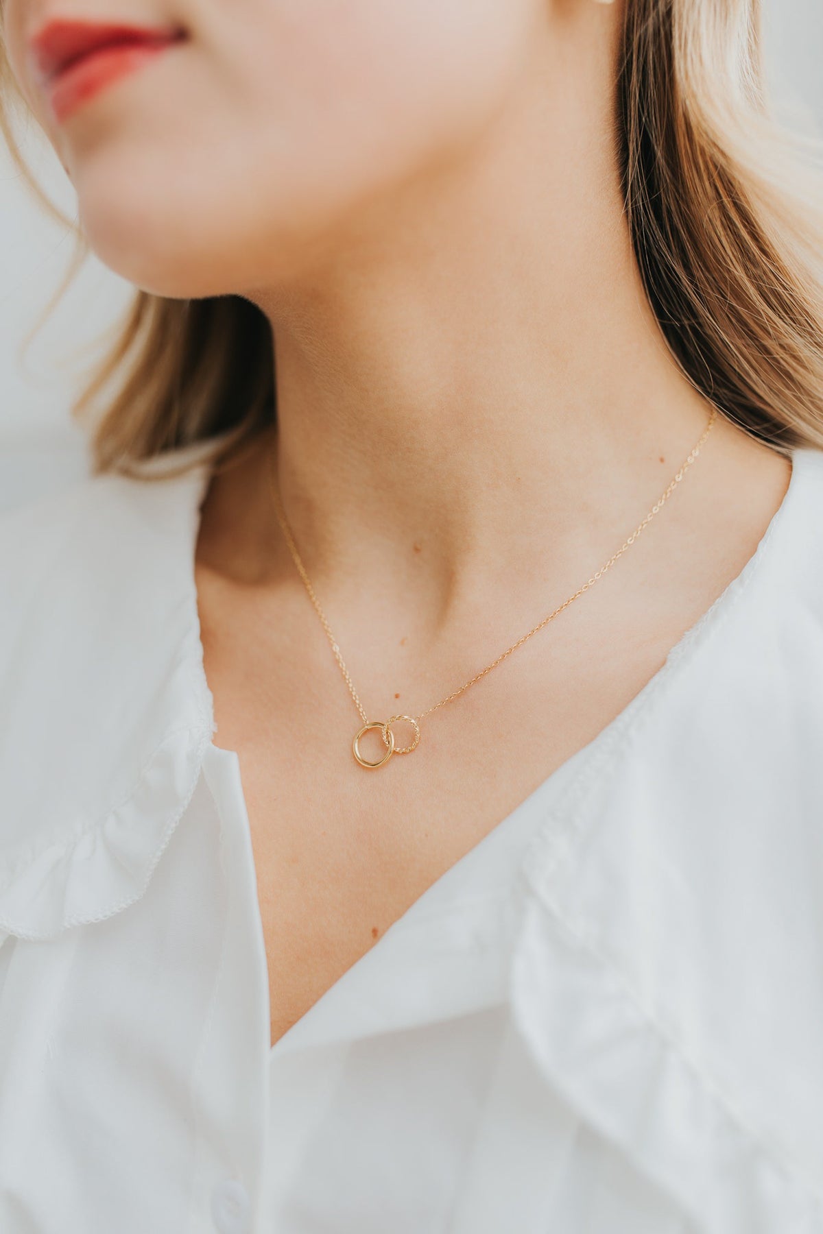 Close-up of The Mia Necklace showing two interlocking gold circles, one smooth and one textured, on a delicate adjustable chain.