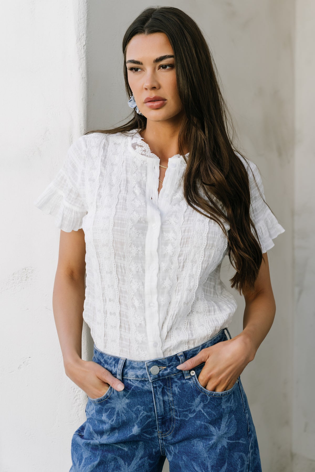Side-angle of model wearing the Zara Lace Top illustrating short ruffle sleeves, unlined silhouette, and how the textured cotton drapes on the body.
