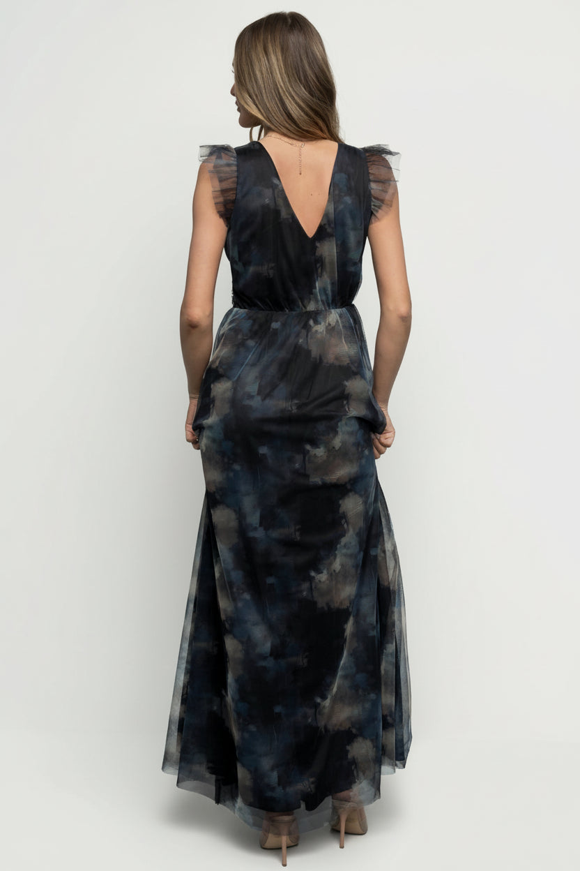 Side view of model walking in Midnight Floral Adelyn Maxi Dress illustrating left leg slit and flowing tulle skirt movement.