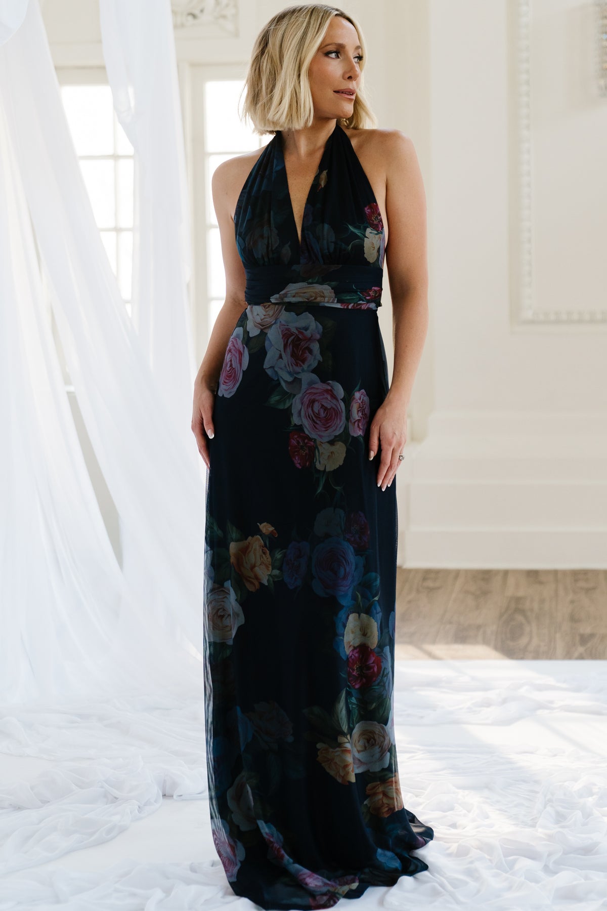 Front view of navy floral halter maxi dress on model showing plunging V-neckline, banded empire waist, and flowing lined skirt for coverage.