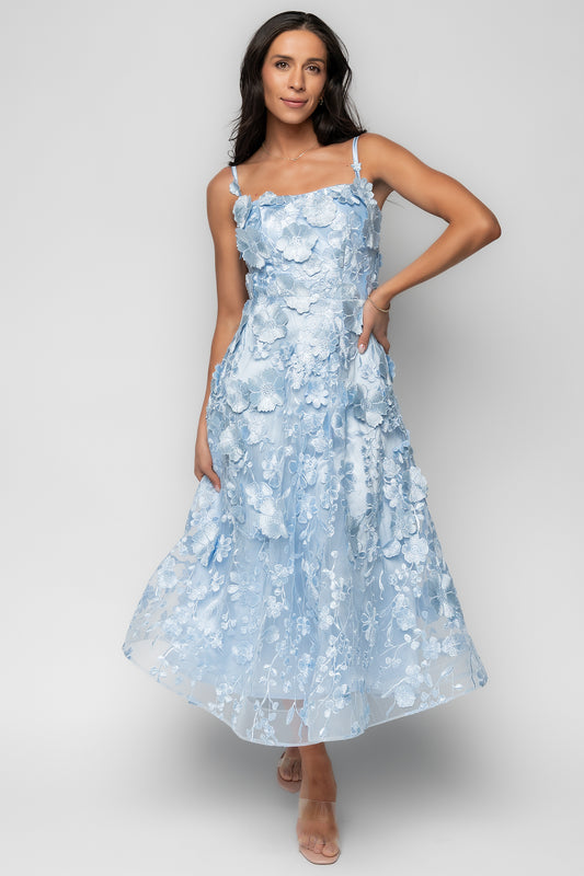 Front view of light blue midi dress on model showing square neckline, adjustable straps, and delicate floral appliqué over mesh.