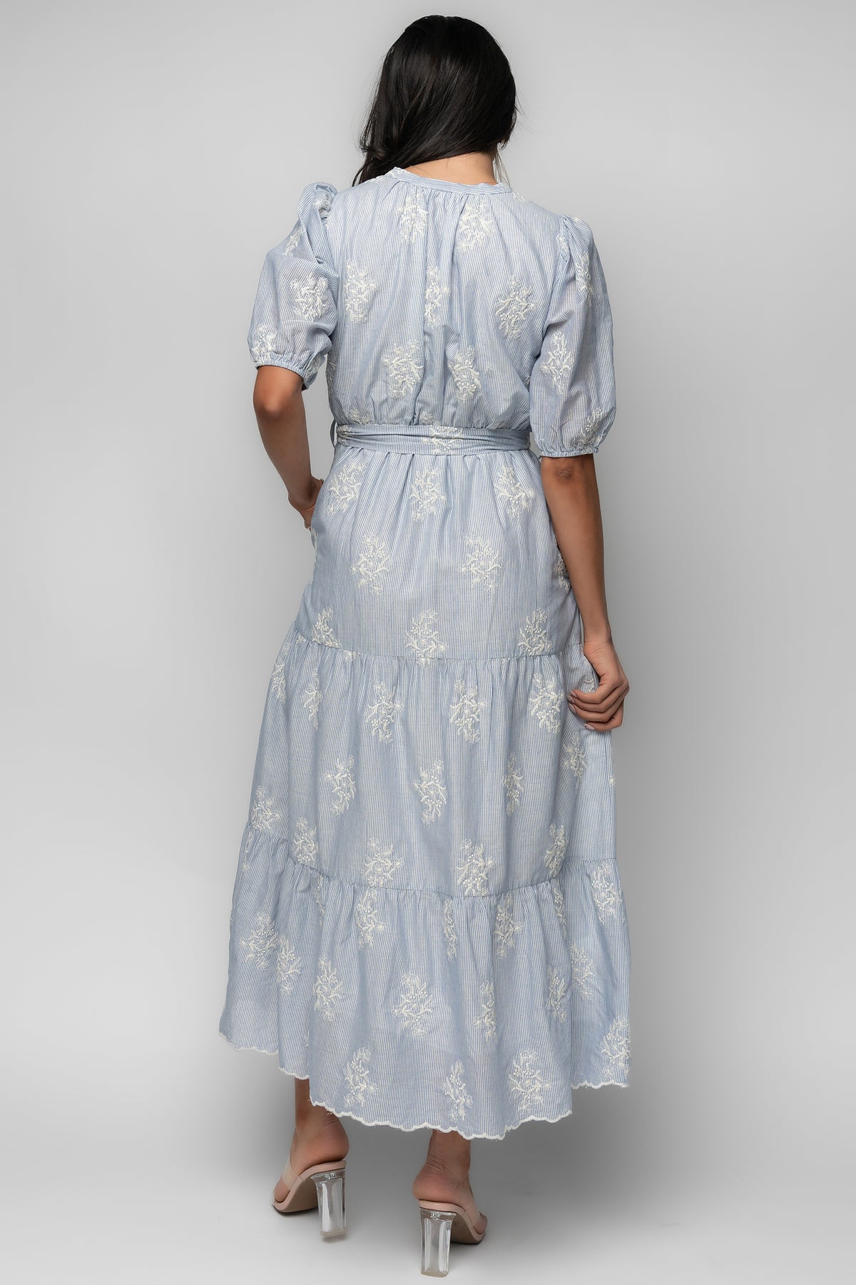 Side view highlighting functional side pocket, removable waist tie, and tiered silhouette with scalloped hem in soft cotton fabric.