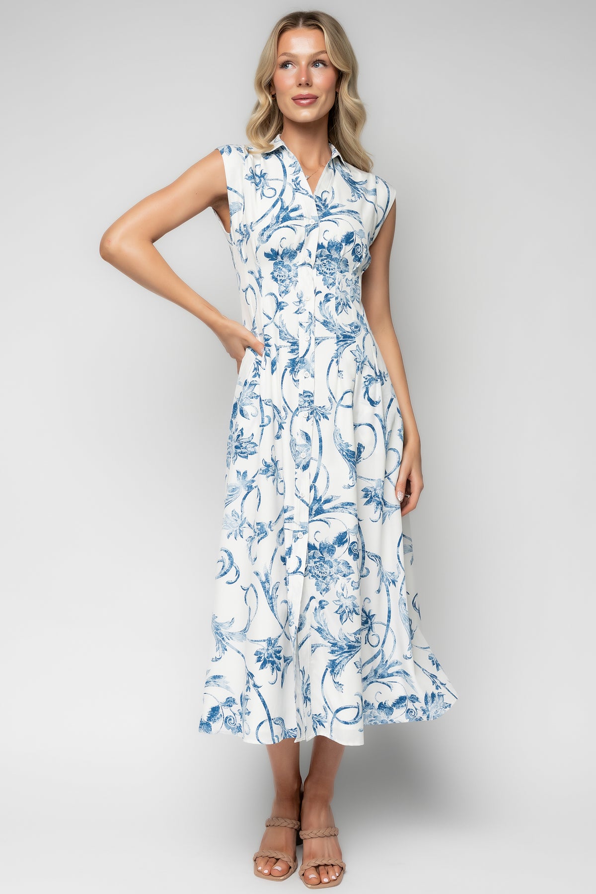 Full-length model view of Tobias midi dress showing midi hem, tailored waist, and flowing skirt in off-white with scattered blue florals.