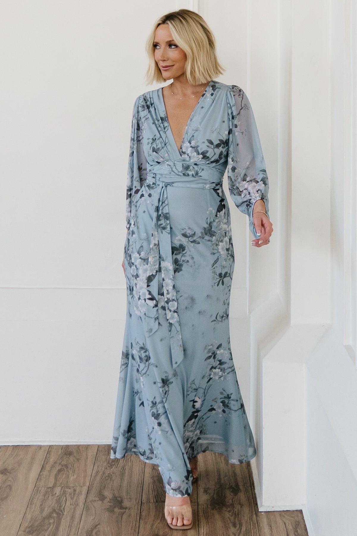 Angled model shot showing long sheer sleeves with asymmetrical length and elastic cuffs, plus flowing skirt movement.