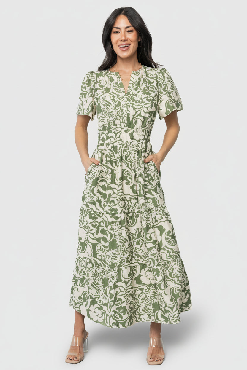 Front view of Aventura Tiered Midi Dress in ivory and green floral print on mannequin, showing V-neck and short gathered sleeves.