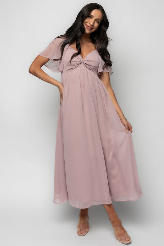 Full-length look at Nora Midi Dress in dusty mauve styled with short flutter sleeves and empire waist, photographed on a model at studio lighting.