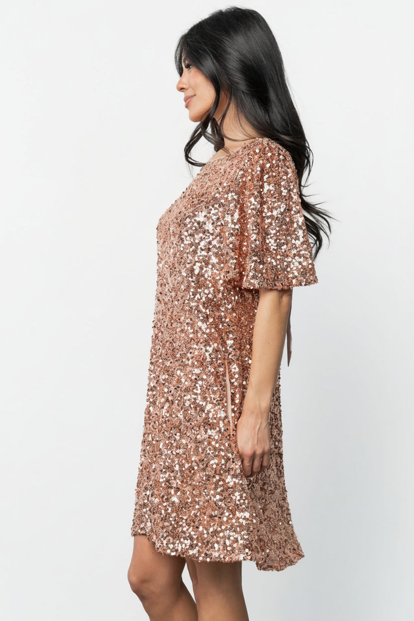 Side view of the rose gold Asta dress on model, focusing on the hidden side pocket and smooth shift silhouette.