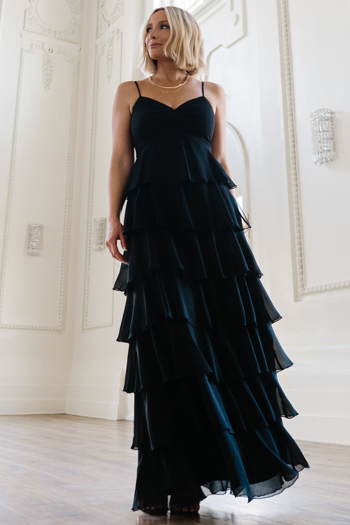 Front view of Tiana Tiered Chiffon Maxi Dress in black on model, showing V-neck, gathered bust, adjustable spaghetti straps, and layered ruffle skirt.