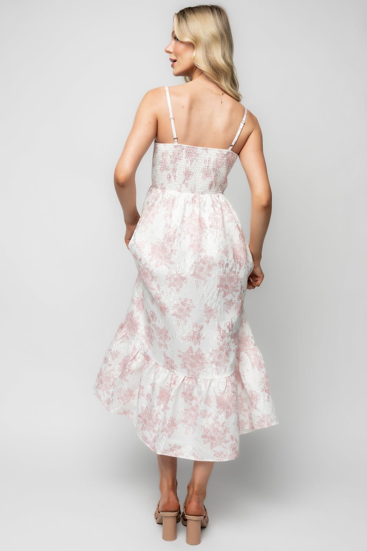 Model wearing Cherie midi dress walking outdoors with hands in side pockets, showing natural movement of tiered skirt.