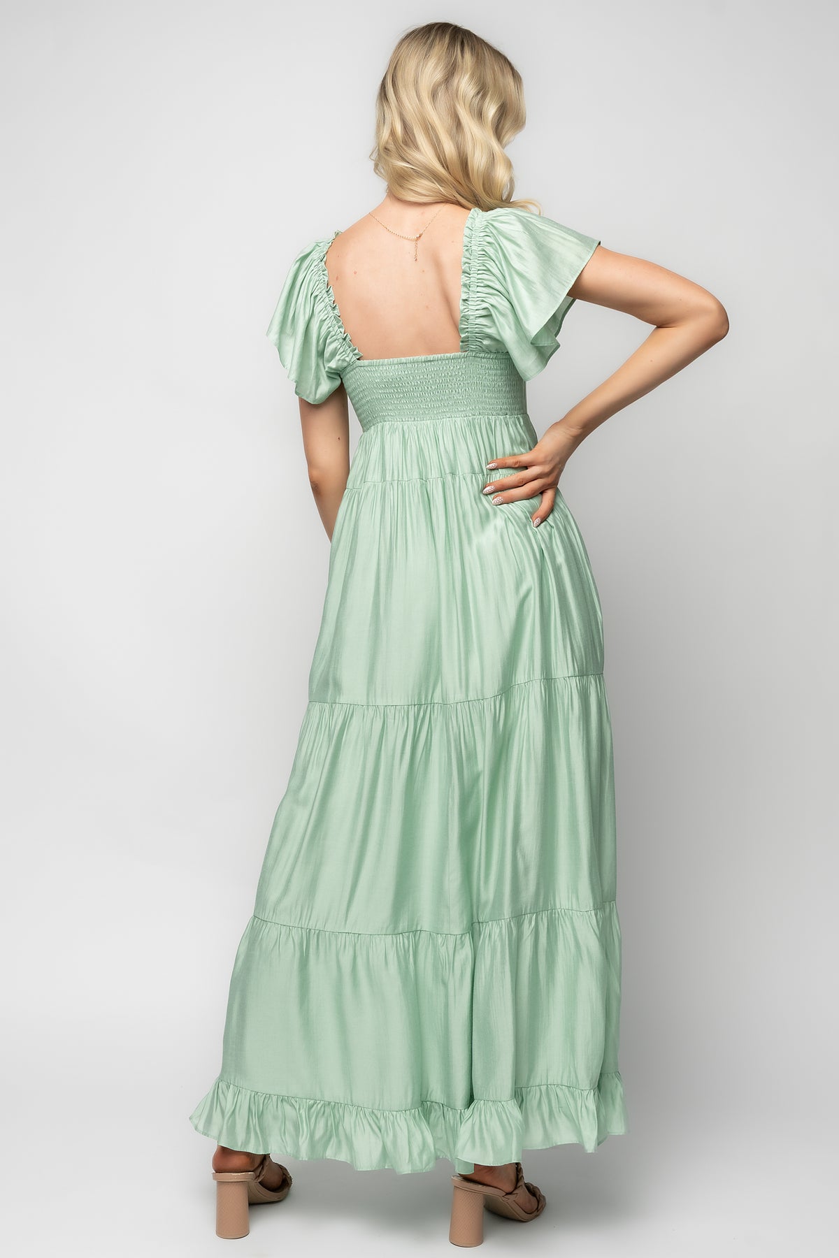 Back view of the Agatha Maxi Dress in light sage emphasizing the smocked back panel and gathered tiers for stretch and comfortable fit.