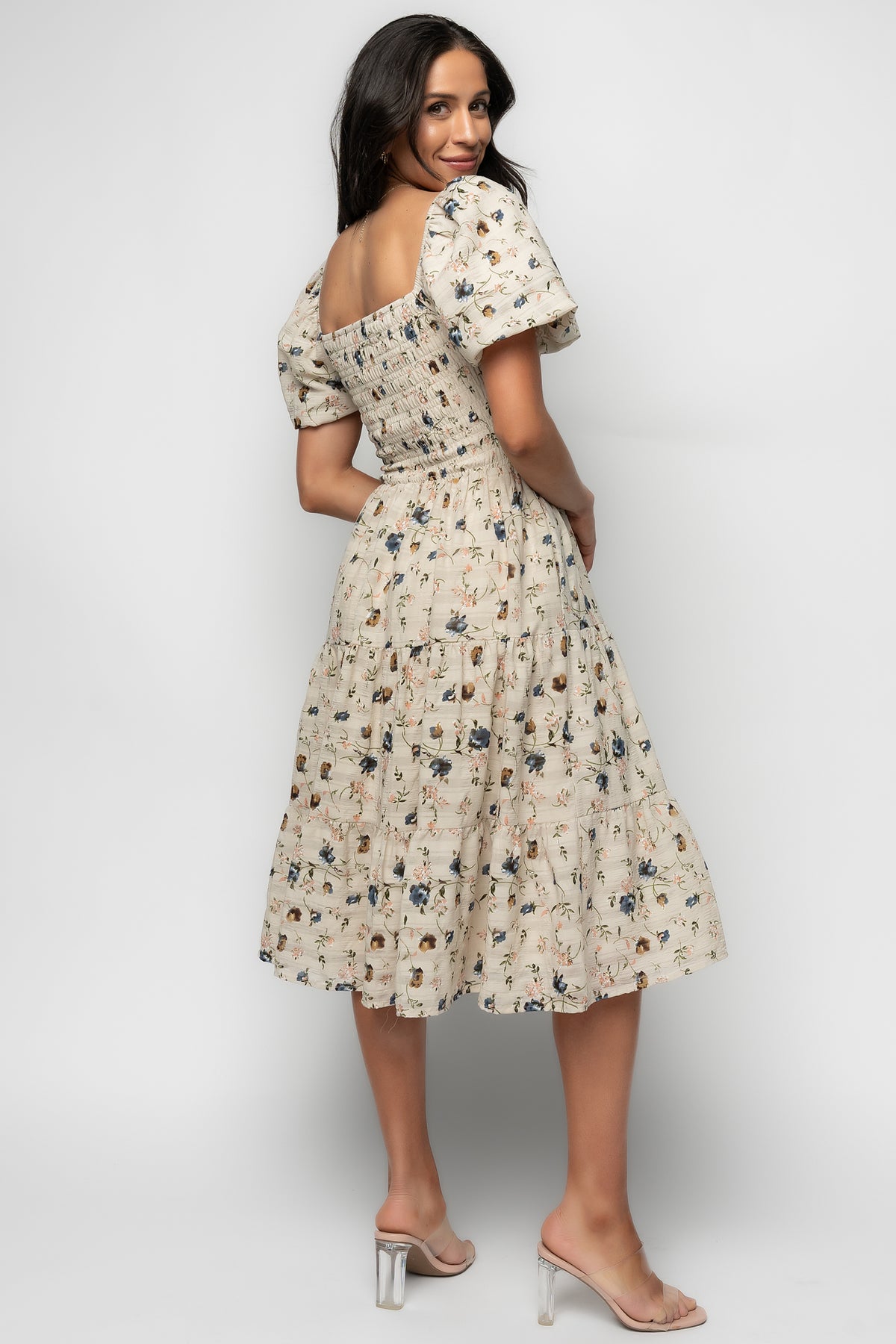 Model wearing Mattea smocked midi dress in beige floral, displaying full length, lining opacity, and relaxed fit across tiers.