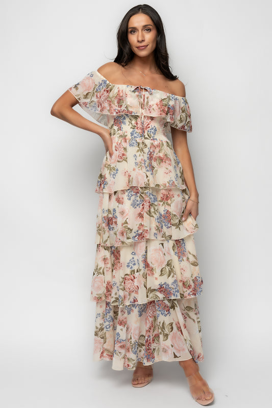 Model wearing multi floral off-shoulder maxi showing single tiered bust ruffle and flattering smocked waist; lightweight chiffon drape visible.