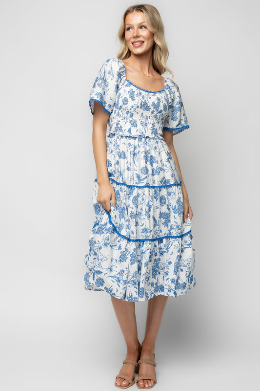 Three-quarter model view of the Freya Tiered Midi Dress in white and blue floral, highlighting tiered skirt length and overall silhouette.