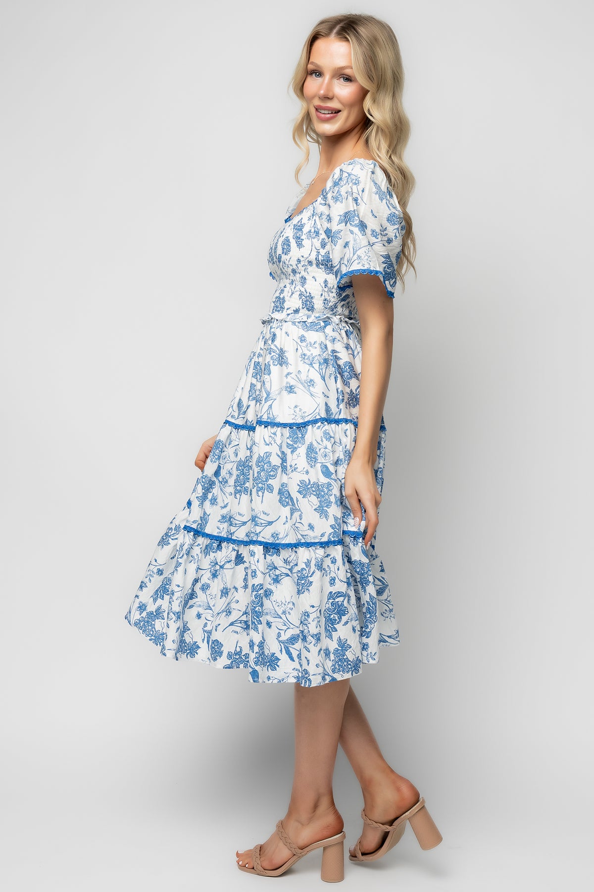 Detail shot of scalloped piping and fabric print showing off-white ground with blue floral motifs and fabric drape.
