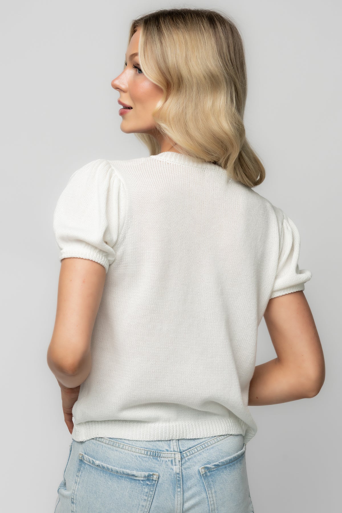 Back and side view of off-white Eulalie cardigan on model, showing overall fit, short sleeve length and textured floral appliqué.