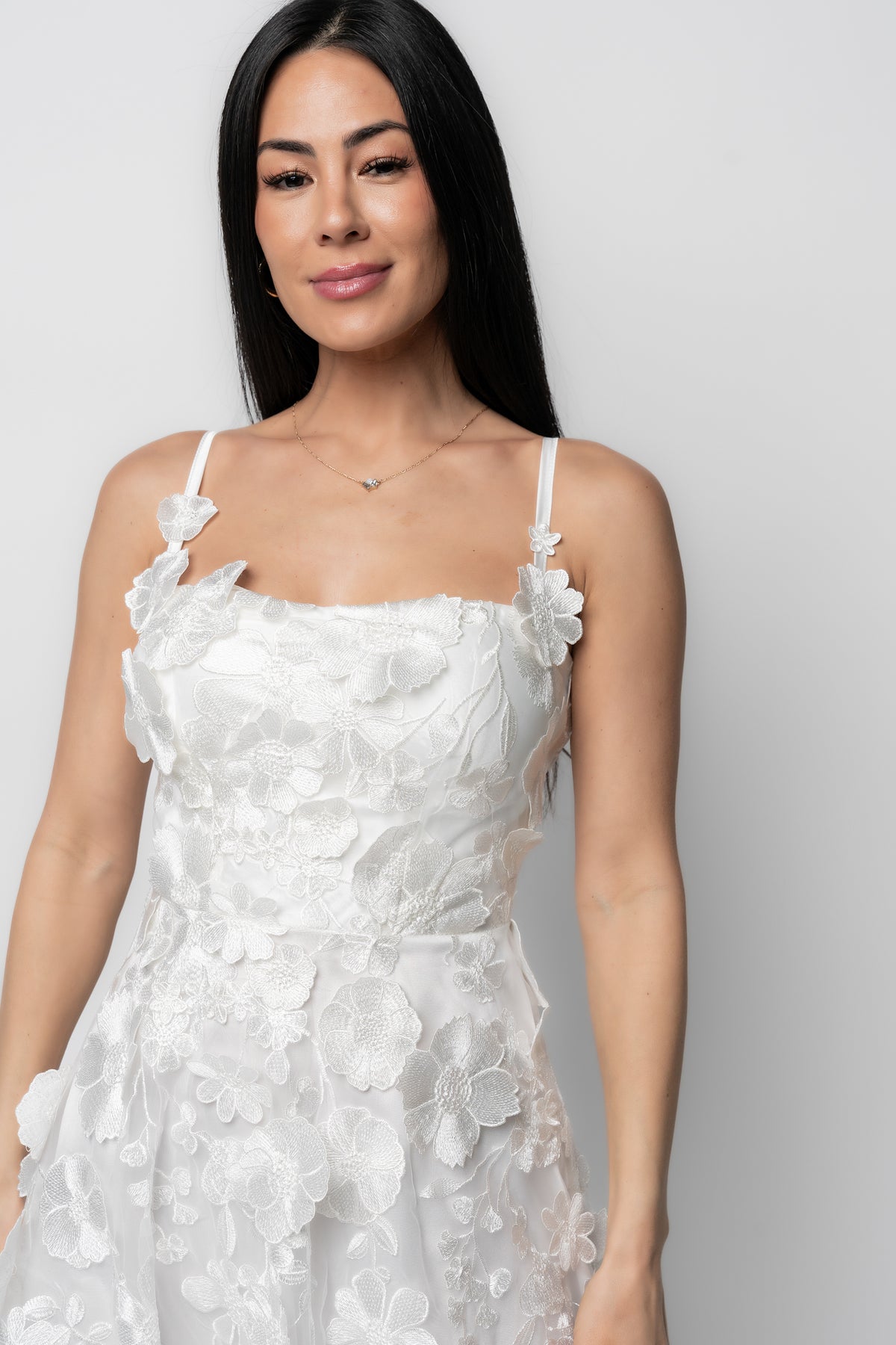 Three-quarter profile of the Soleil ivory midi dress highlighting the layered floral appliqué and structured bottom hem.