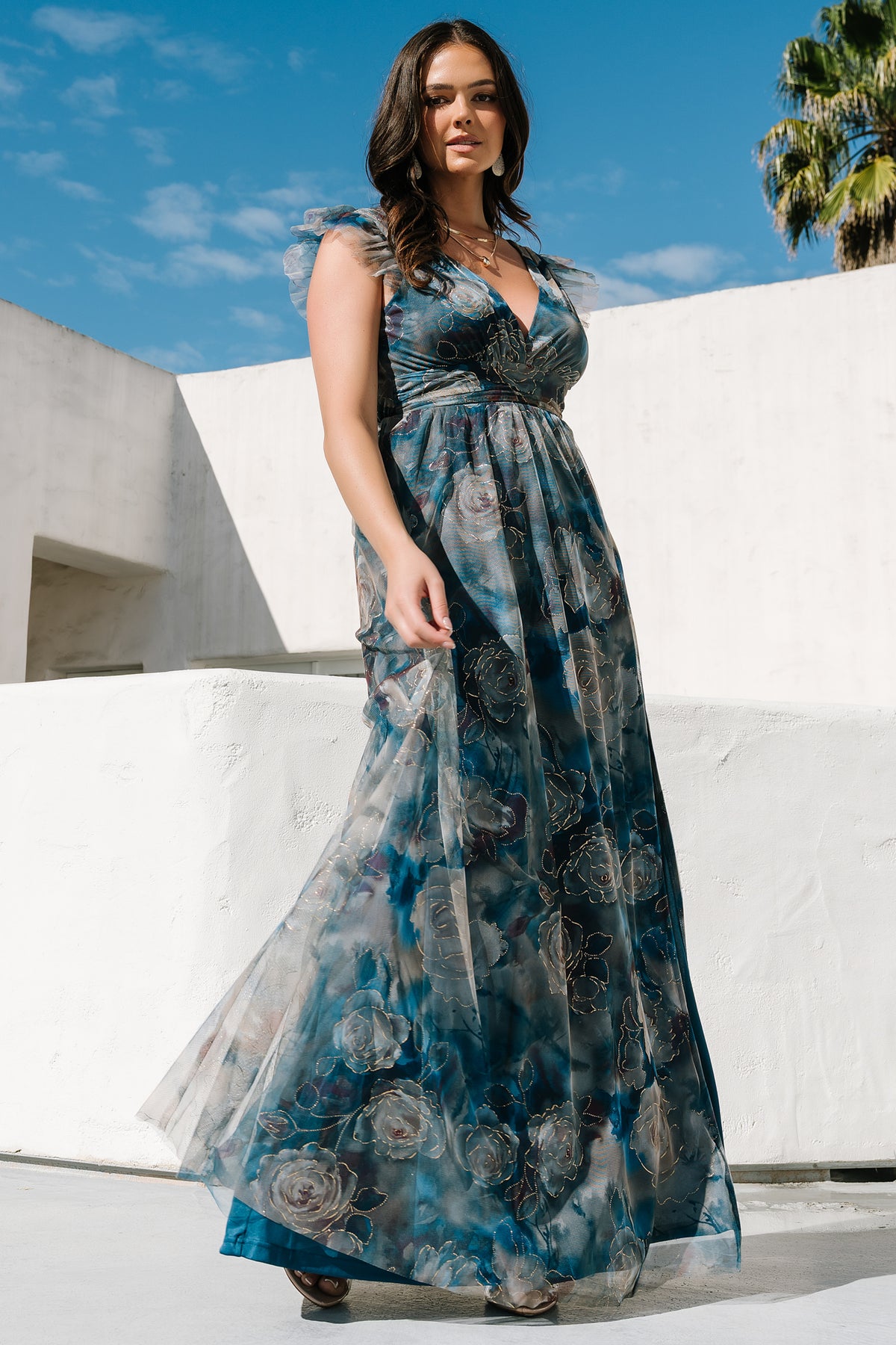 Model walking in the blue floral Adelyn Maxi Dress demonstrating skirt movement and left leg slit for added flow and comfort.