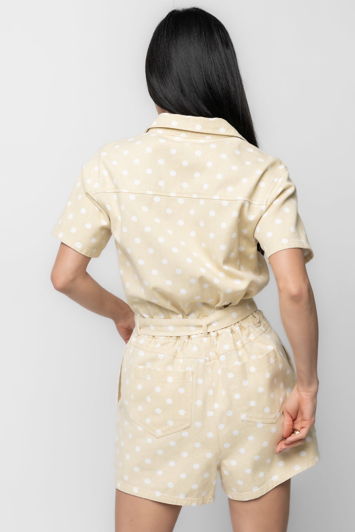 Close-up of fabric and print: light yellow twill denim woven texture with white polka dots and reinforced stitching.