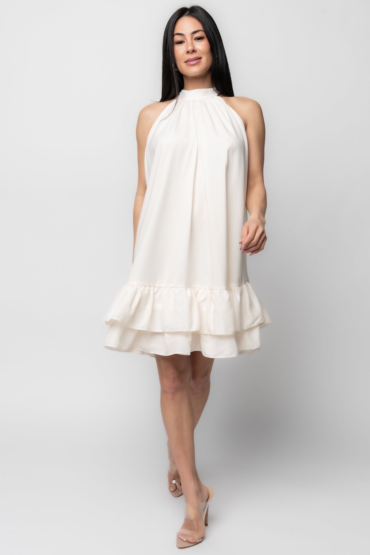 Front view of the Lulu ruffle halter mini dress in cream, showing the adjustable halter tie, tiered ruffles, and satin-like sheen.