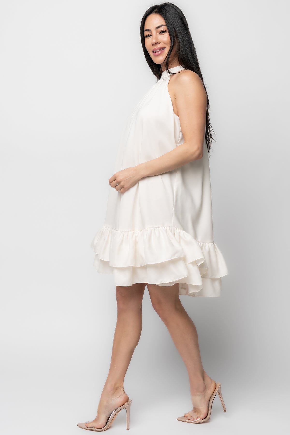 Back view close-up of the cream halter dress showing the discreet back zipper, ruffled tiers, and fully lined interior.
