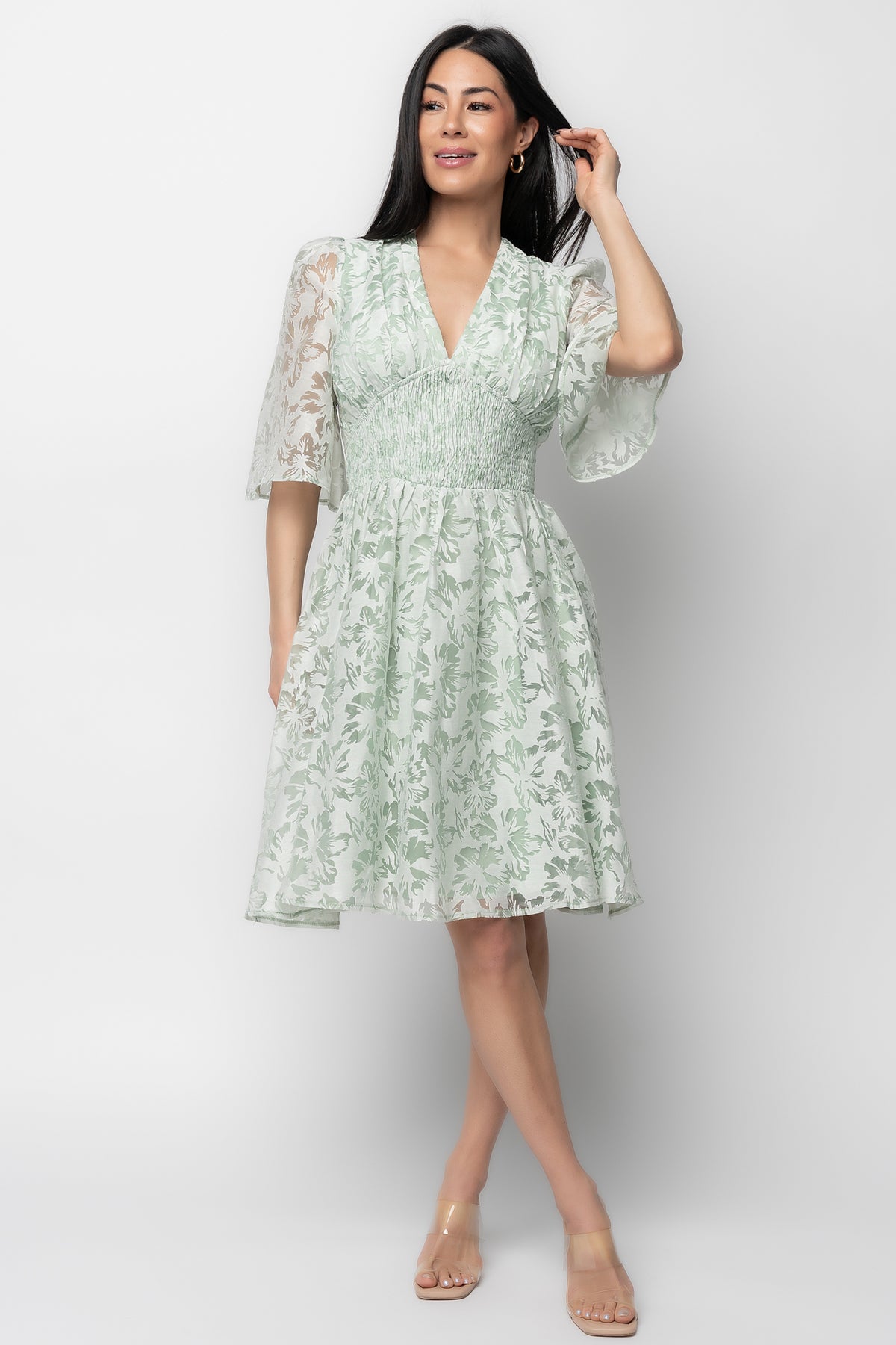 Front view of model wearing Bonnie Short Dress in sage floral jacquard, showing deep V-neckline, smocked empire waist, and mini hemline.