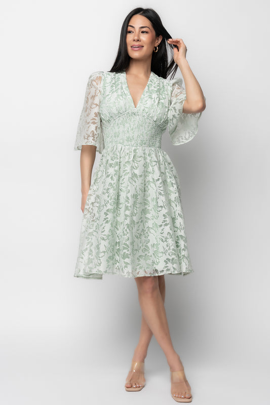 Front view of model wearing Bonnie Short Dress in sage floral jacquard, showing deep V-neckline, smocked empire waist, and mini hemline.